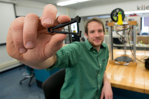 Man holding a small 3D printed umbilical cord clamp