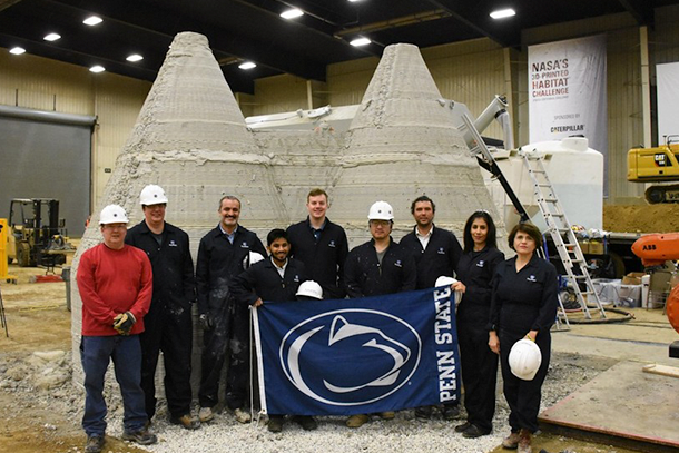 Members of the Penn State team pose in front of the first fully enclosed 3D-printed housing structure