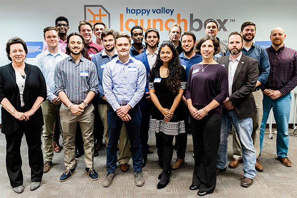 A group of people pose for a photo in front of the Happy Valley LaunchBox decal.