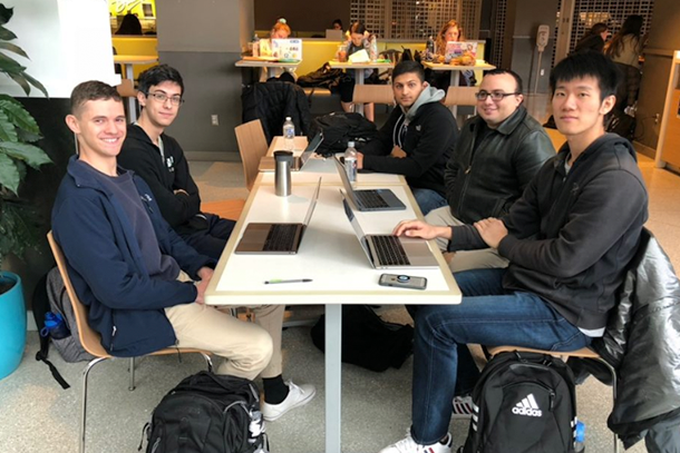 Five male students sit around a table